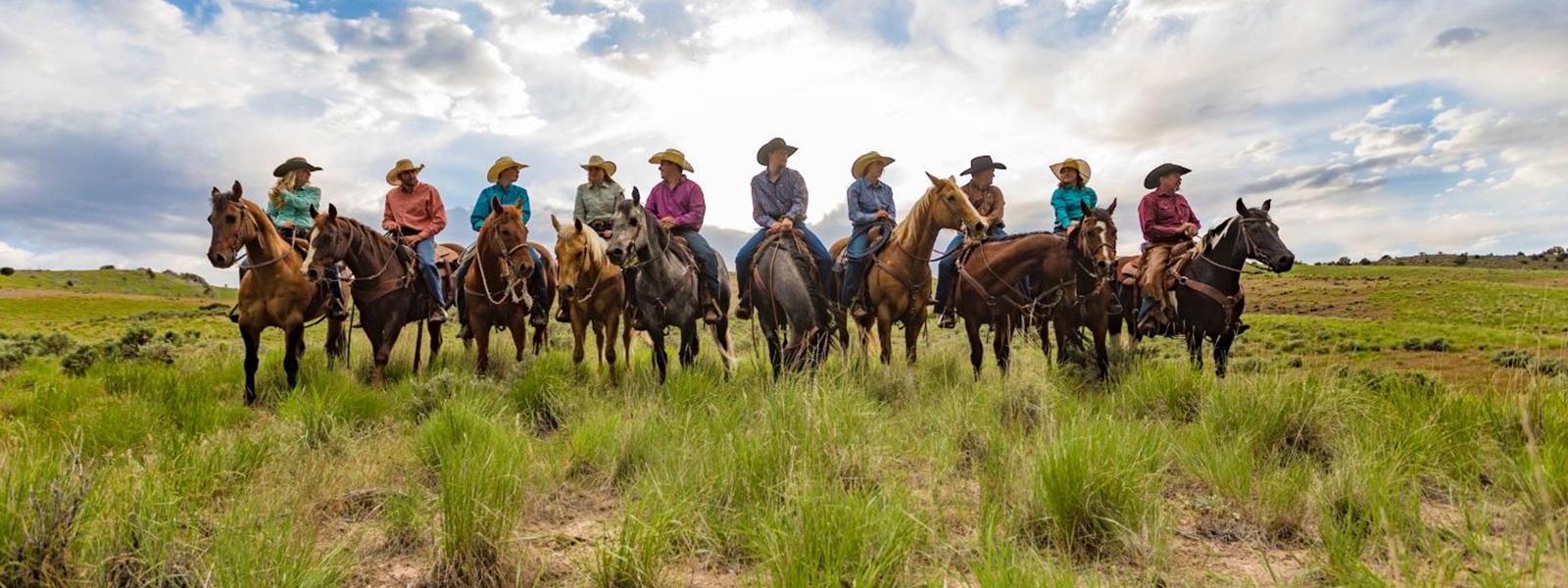 Backlit Line Up of a Group of Cowboys and Cowgirls on horseback on the prairie
